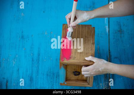 Holzmöbel mit Kreidemalerei aus menschlicher Hand. Alte Holzmöbel werden mit brandneuer, farbenfroher Kreidefarbe erneuert. Die Innendekoration wird neu gestaltet Stockfoto