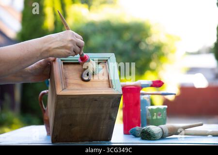 Holzmöbel mit Kreidemalerei aus menschlicher Hand. Alte Holzmöbel werden mit brandneuer, farbenfroher Kreidefarbe erneuert. Die Innendekoration wird neu gestaltet Stockfoto
