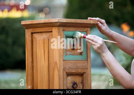 Holzmöbel mit Kreidemalerei aus menschlicher Hand. Alte Holzmöbel werden mit brandneuer, farbenfroher Kreidefarbe erneuert. Die Innendekoration wird neu gestaltet Stockfoto