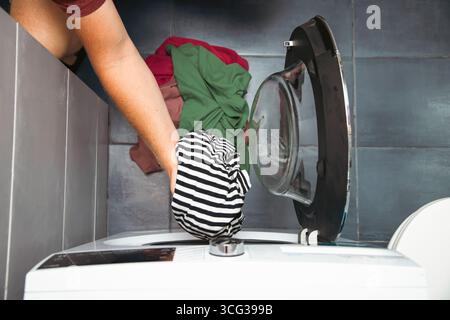 Blick von oben auf einen Mann, der schmutzige Kleidung in die Waschmaschine legte. Stockfoto