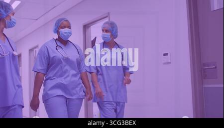 Drei Angestellte im Krankenhausflur gehen mit blauen Peelings Gesichtsmasken Haarnetze mit Stethoskopen Stockfoto