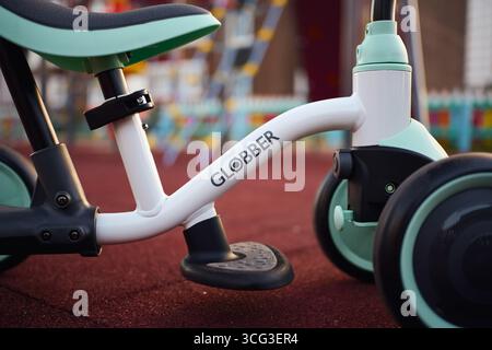 Tyumen, Russland-8. Juli 2025: Balancerad globber parkt bei Tageslicht auf Spielplatzfläche in der Nähe von farbenfrohen Spielstrukturen Stockfoto