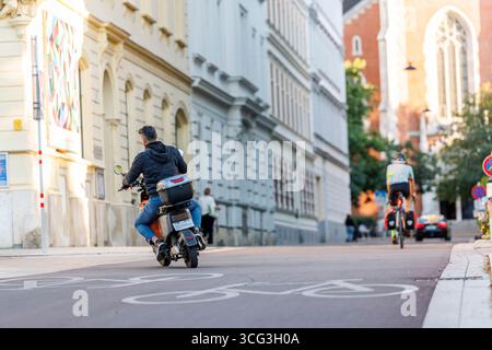 In Wien werden Essenszustellungen durch Lieferdienste wie Foodora, Wolt oder Lieferando durchgeführt. Viele Zusteller befahren mit elektrischen Rollern die Fahrradwege, das für zunehmende Kritik sorgt. Es werden bereits Fahrverbote auf Fahrradwegen für diese Elektromopeds diskutiert. Im Bild: Ein Zustellfahrer mit einem Elektroroller auf einem Fahrradweg am 25. August 2025 auf der Argentinierstraße in Wien. // in Wien erfolgt die Lieferung von Lebensmitteln durch Lieferdienste wie Foodora, Wolt oder Lieferando. Viele Lieferfahrer verwenden elektrische Roller auf Fahrradwegen, was zu einer Zunahme der Fahrten geführt hat Stockfoto