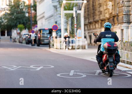 In Wien werden Essenszustellungen durch Lieferdienste wie Foodora, Wolt oder Lieferando durchgeführt. Viele Zusteller befahren mit elektrischen Rollern die Fahrradwege, das für zunehmende Kritik sorgt. Es werden bereits Fahrverbote auf Fahrradwegen für diese Elektromopeds diskutiert. Im Bild: Ein Zustellfahrer mit einem Elektroroller auf einem Fahrradweg am 25. August 2025 auf der Argentinierstraße in Wien. // in Wien erfolgt die Lieferung von Lebensmitteln durch Lieferdienste wie Foodora, Wolt oder Lieferando. Viele Lieferfahrer verwenden elektrische Roller auf Fahrradwegen, was zu einer Zunahme der Fahrten geführt hat Stockfoto