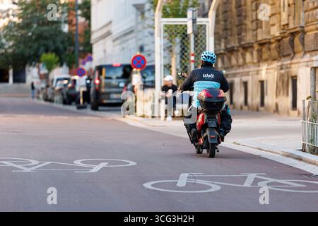 In Wien werden Essenszustellungen durch Lieferdienste wie Foodora, Wolt oder Lieferando durchgeführt. Viele Zusteller befahren mit elektrischen Rollern die Fahrradwege, das für zunehmende Kritik sorgt. Es werden bereits Fahrverbote auf Fahrradwegen für diese Elektromopeds diskutiert. Im Bild: Ein Zustellfahrer mit einem Elektroroller auf einem Fahrradweg am 25. August 2025 auf der Argentinierstraße in Wien. // in Wien erfolgt die Lieferung von Lebensmitteln durch Lieferdienste wie Foodora, Wolt oder Lieferando. Viele Lieferfahrer verwenden elektrische Roller auf Fahrradwegen, was zu einer Zunahme der Fahrten geführt hat Stockfoto