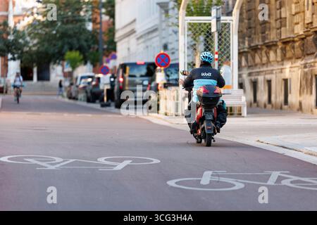 In Wien werden Essenszustellungen durch Lieferdienste wie Foodora, Wolt oder Lieferando durchgeführt. Viele Zusteller befahren mit elektrischen Rollern die Fahrradwege, das für zunehmende Kritik sorgt. Es werden bereits Fahrverbote auf Fahrradwegen für diese Elektromopeds diskutiert. Im Bild: Ein Zustellfahrer mit einem Elektroroller auf einem Fahrradweg am 25. August 2025 auf der Argentinierstraße in Wien. // in Wien erfolgt die Lieferung von Lebensmitteln durch Lieferdienste wie Foodora, Wolt oder Lieferando. Viele Lieferfahrer verwenden elektrische Roller auf Fahrradwegen, was zu einer Zunahme der Fahrten geführt hat Stockfoto