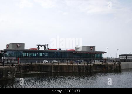 Moderner Fährhafen der Isle of man in Liverpool mit Blick auf den Hafen, Fahrzeugen und Flagge, die den Seeverkehr und die regionalen Reiseverbindungen des Vereinigten Königreichs hervorheben. Stockfoto