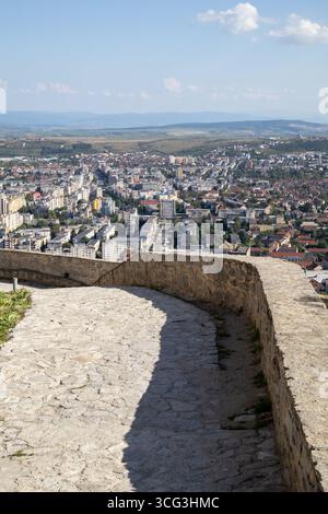 Blick auf die rumänische Stadt deva von einem historischen Steinweg, der zur alten Zitadelle führt, unter einem klaren Sommerhimmel Stockfoto