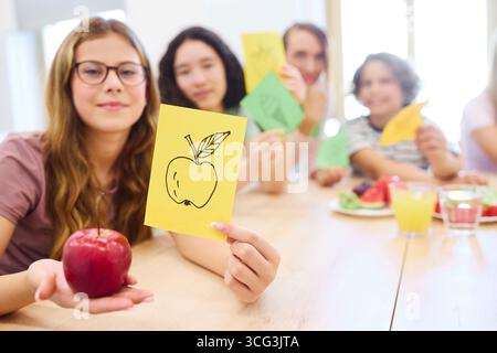 Eine Gruppe von Schülern, die an einer lebendigen und interaktiven Lernaktivität teilnehmen, während sie gesunde Snacks teilen und Lernthemen erkunden Stockfoto