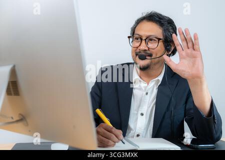Ein junger Geschäftsmann, der an einer Online-Videokonferenz teilnimmt und für Fernarbeit, digitale Kommunikation und modernen Unternehmensstil steht Stockfoto