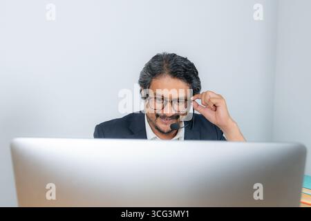 Ein junger Geschäftsmann, der an einer Online-Videokonferenz teilnimmt und für Fernarbeit, digitale Kommunikation und modernen Unternehmensstil steht Stockfoto