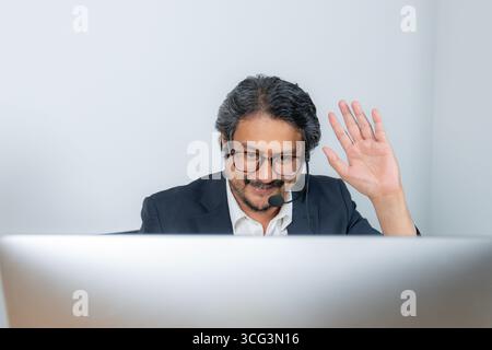 Ein junger Geschäftsmann, der an einer Online-Videokonferenz teilnimmt und für Fernarbeit, digitale Kommunikation und modernen Unternehmensstil steht Stockfoto