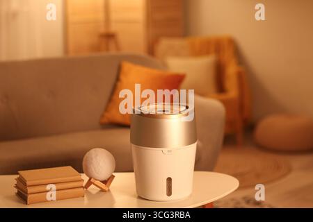 Moderner Luftbefeuchter auf Couchtisch im Wohnzimmer am Abend Stockfoto