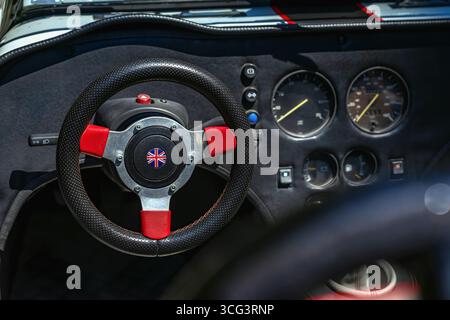 Lenkrad mit britischer Flagge, Armaturenbrett. Nahaufnahme eines maßgefertigten Lenkrads mit Union Jack Emblem, Vintage-Armaturenbrett. Britisches Konzept Stockfoto
