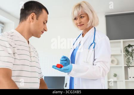 Endokrinologin zeigt Schilddrüsenmodell bei männlichem Patienten in der Klinik Stockfoto