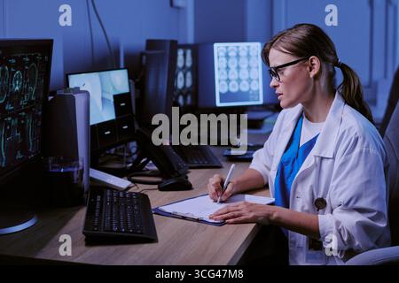 Kaukasische junge Erwachsene Frau Doktor Analyse von Gehirnscans und Notizen Stockfoto