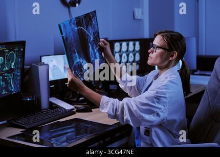 Kaukasische junge Erwachsene Radiologin untersucht Röntgenscan im Krankenhausbüro Stockfoto
