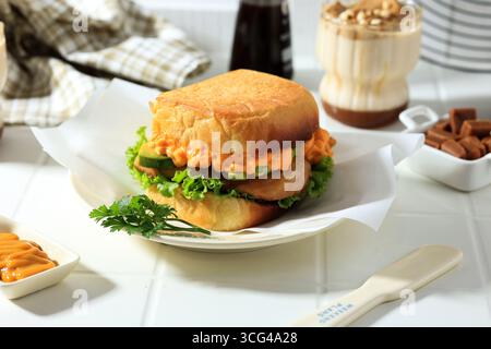Sandwich mit Huhn, Avocado, Käsesauce und Salat auf weißem Holztisch Stockfoto