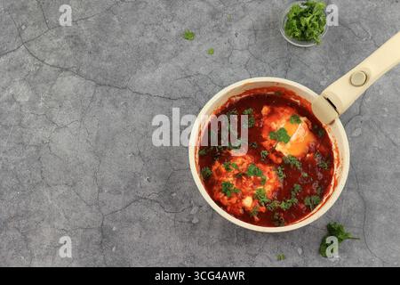 Shakshuka in einer Bratpfanne. Eier in würziger Tomaten-Pfeffersoße gepochiert. Draufsicht mit Kopierbereich für Text Stockfoto
