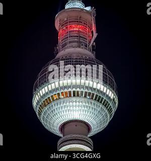 Nächtlicher quadratischer Schnitt des oberen Teils des Berliner Fernsehturms mit hohem Kontrast zum schwarzen Himmel. Stockfoto