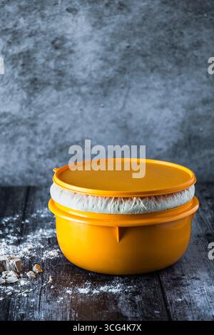 Schüssel mit aufsteigendem Hefeteig und frischer Hefe auf dem dunklen Tisch, Kopierraum, vertikal Stockfoto
