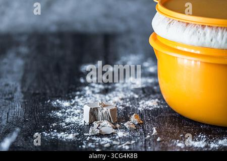 Schüssel mit aufsteigendem Hefeteig und frischer Hefe auf dem dunklen Tisch, Kopierraum Stockfoto