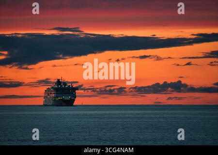 Kreuzfahrtschiff bei Sonnenuntergang auf offenem Meer - szenischer Blick auf den See Stockfoto