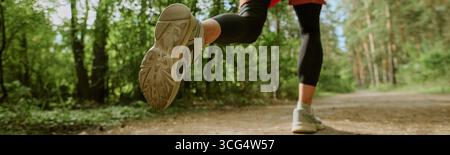 Kopfzeile mit einer jungen Erwachsenen, kaukasischen Frau, die draußen auf dem Forest Trail joggt Stockfoto