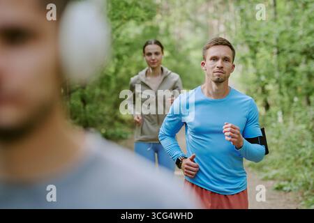 Kaukasischer junger Mann, der draußen mit Young Woman in Forest Trail joggt Stockfoto