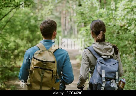 Junger Erwachsener kaukasischer Mann und Frau, die gemeinsam auf dem Forest Trail spazieren Stockfoto