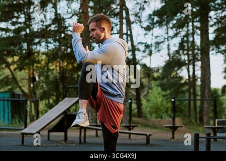 Kaukasischer Junger Erwachsener Mann, Der Im Freien Ein Hohes Knie-Workout Durchführt Stockfoto