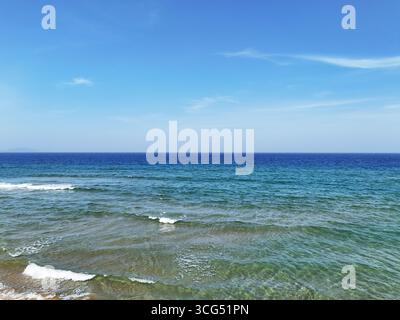 Hochwinkelblick auf das blaue Meer und die Wellen unter klarem Himmel in Sanya. Stockfoto