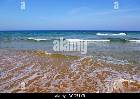 Meereswellen und Sandstrand in Sanya unter blauem Himmel. In Sanya, Hainan, China Stockfoto