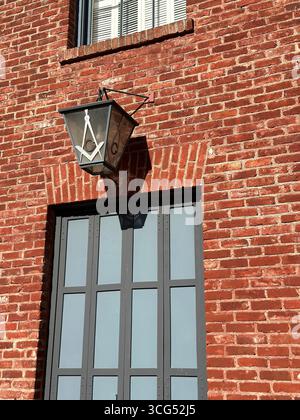 Eine Laterne mit dem Freimaurerplatz und dem Kompass-Symbol hängt außen an einem historischen Gebäude aus roten Backsteinen. Stockfoto