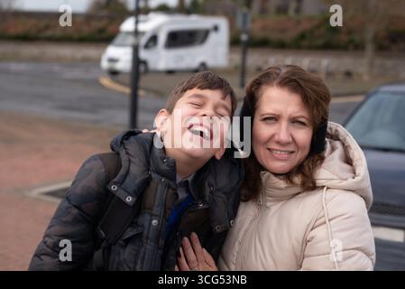Eine Mutter und ihr Sohn teilen einen fröhlichen Moment im Freien in Winterkleidung. Die Szene fängt Wärme und Glück ein und unterstreicht die starke Bindung der Familie Stockfoto