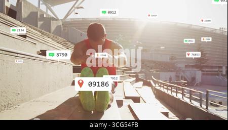 Ein Mann in rotem Tank, der sich auf Stadiontribünen in Richtung Füße streckt, mit fließenden Kennzahlen Stockfoto