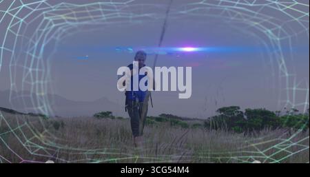 Wanderritter in blauer Weste, brauner Rucksack in windgepeitschtem Grasland mit Drahtrahmen-Überzug Stockfoto