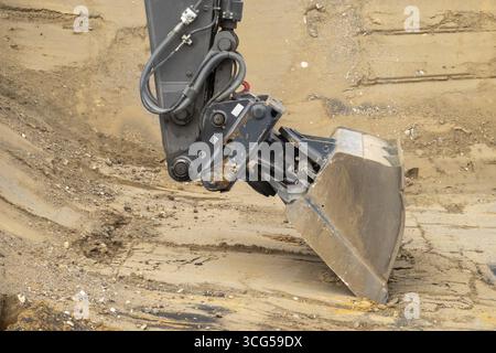 Baggerlöffel, der in den Boden gräbt, auf einer Baustelle arbeitet Stockfoto