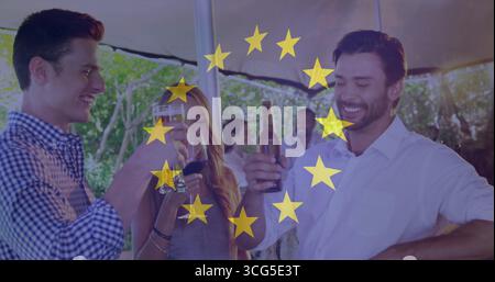 Auf der Terrasse im Hinterhof unter Sonnenschirm tosten Freunde mit braunen Flaschen und Weinglas Stockfoto