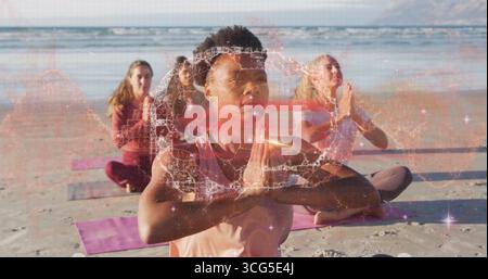 Meditierende Erwachsene Frau in rosa ärmelloser Spitze mit Gebetsposition am Sandstrand, mit Yogamatten Stockfoto