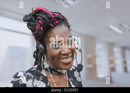 Freundlicher afroamerikanischer Kundendienstmitarbeiter, der ein Headset trägt, bietet technischen Support und Kundenbetreuung. Professionelles Callcenter o Stockfoto