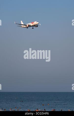 Larnaca, Zypern - 26. Juli 2025: Airbus A320-214 Passagierflugzeug der EasyJet Airline landet über dem Strand, wo Touristen schwimmen und sich sonnen Stockfoto