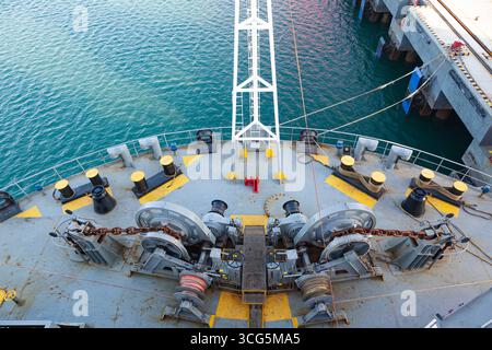 Der Bug eines Frachtschiffes, das am Pier verankert ist, mit Festmacherwinden auf dem Deck, Blick von oben. Stockfoto