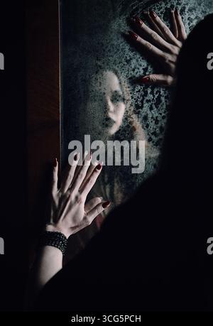 Horrorszene: Verschwommenes Spiegelbild des Geistermädchens im alten schmutzigen Spiegel Stockfoto