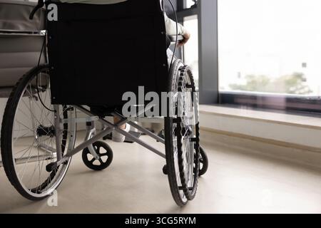 Zugeschnittene Rückansicht einer Frau, die im Rollstuhl am Fenster sitzt Stockfoto