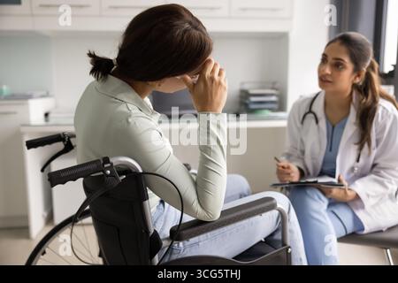 Betreuender junger indischer Traumaarzt mit Patienten im Rollstuhl Stockfoto