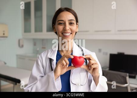Glückliche junge Chirurgin mit rotem Herzen Stockfoto