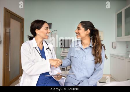 Glückliche Ärztin schüttelt Hand mit indischer Patientin Stockfoto