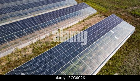 Luftaufnahme moderner Solargewächshäuser mit Photovoltaik-Panels auf Dächern, erneuerbare Energien und nachhaltiges Landwirtschaftskonzept Stockfoto