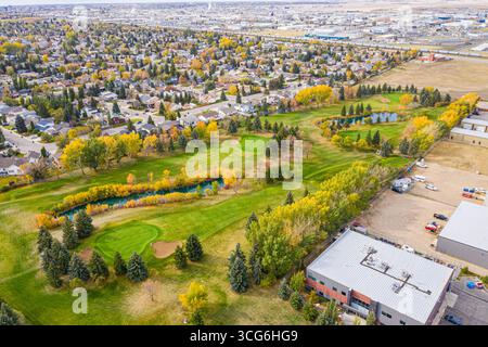 Golfplatz mit grünem Grasgebiet und Teich. Der Golfplatz ist von Häusern und einem Gebäude umgeben Stockfoto